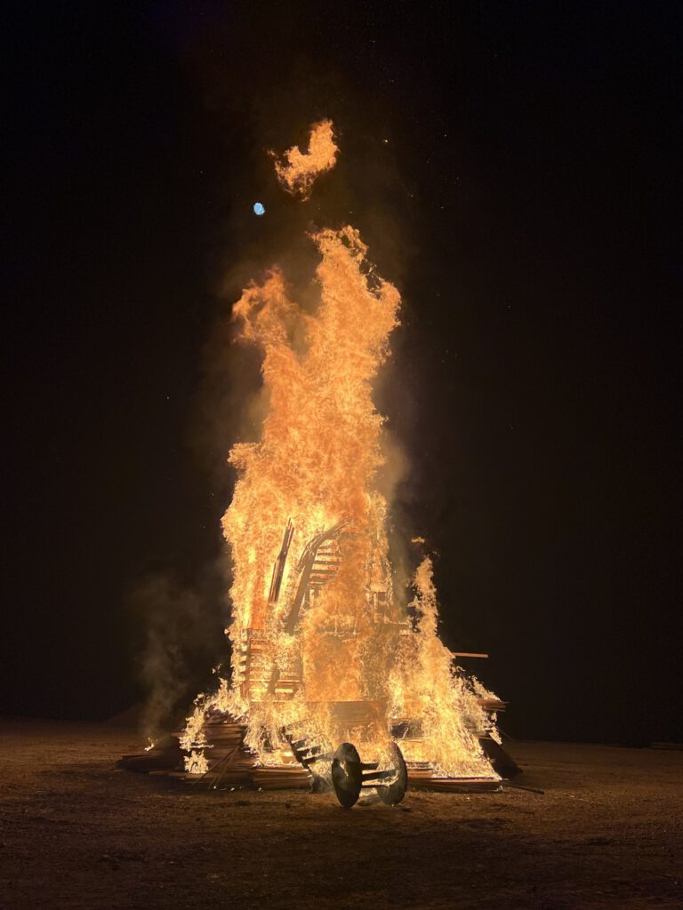The wooden Birding Man effigy fully alight against the night sky